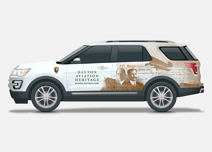 White vehicle with a wrap design with the Wright Brothers on one side and Paul Dunbar on the other.